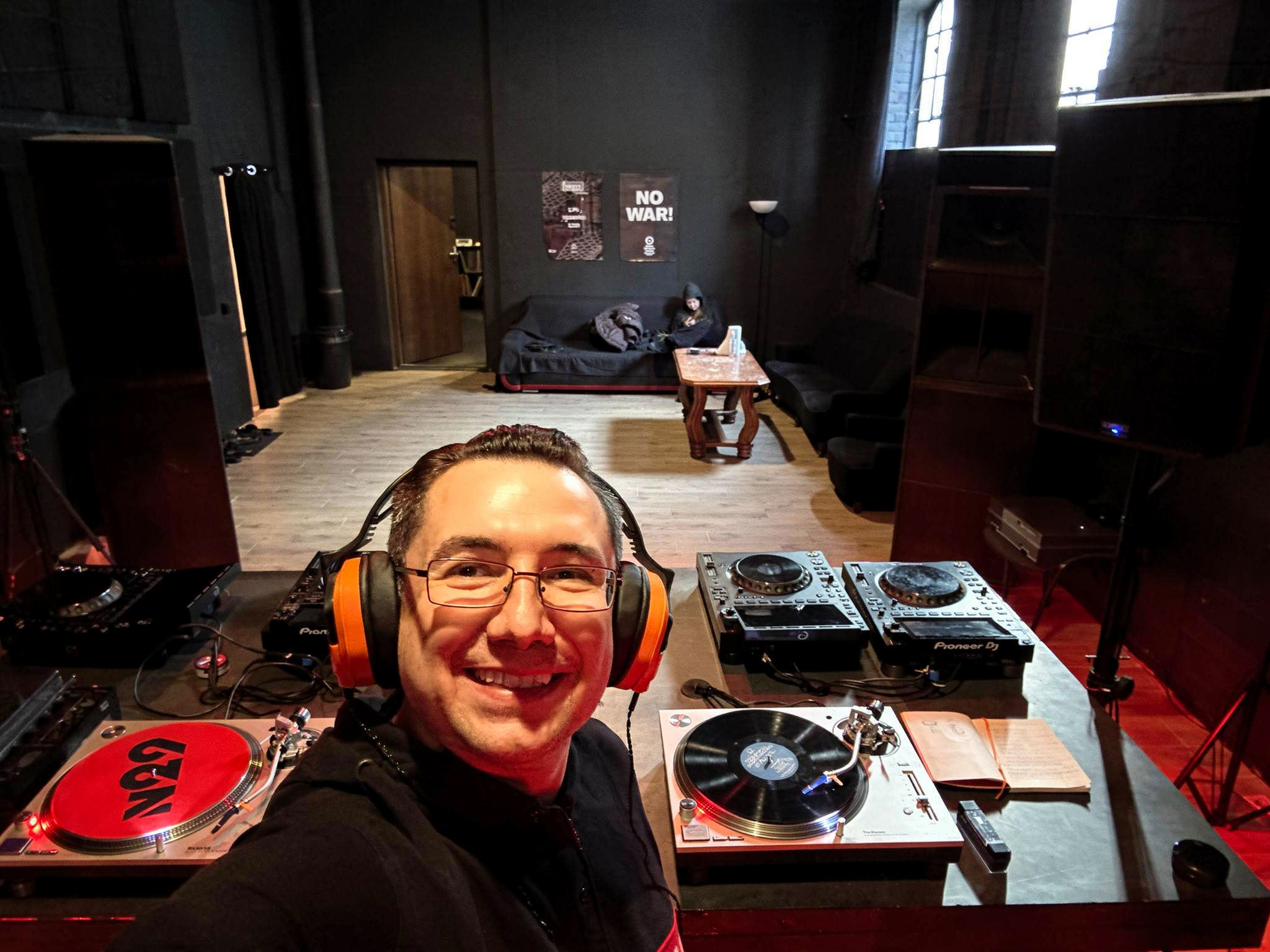 Olek przy konsolecie DJ z winylami i słuchawkami Badger Sound Forge na głowie – Pioneer DJ, dwa talerze